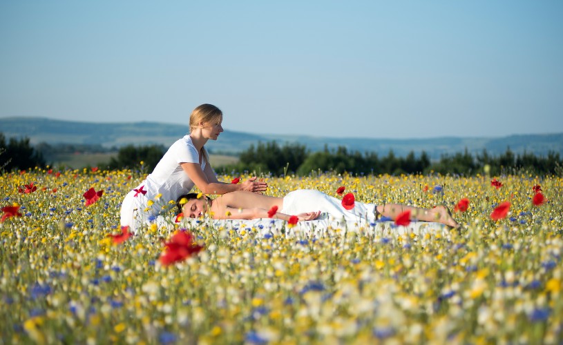 Masseuse giving woman massage in wildflower meadow